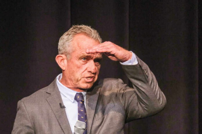 shutterstock2341983441jpg Man in a suit gesturing while speaking into a microphone on stage