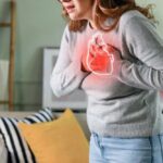 Heart Crisis Explodes–60% Women Doomed Woman holding her chest in discomfort with a heart illustration