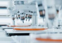 Automated laboratory equipment with robotic arms dispensing liquids into petri dishes