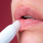 Close-up of a person applying lip balm to their lips