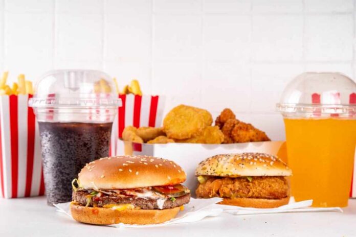 shutterstock_2505627815.jpg A variety of fast food items including burgers, fries, and drinks