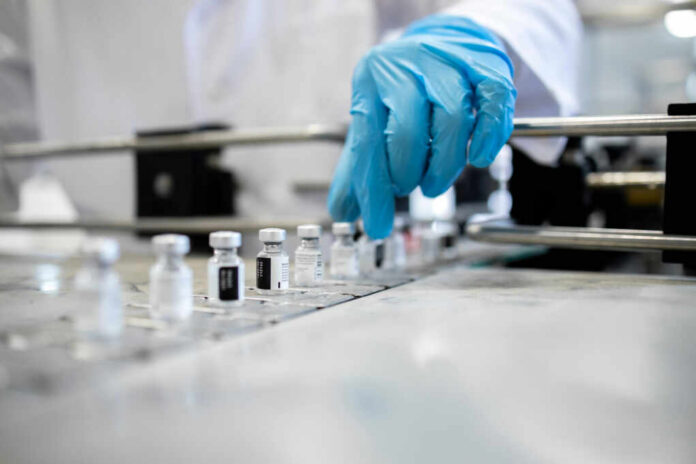 A healthcare professional in a lab preparing vaccine vials