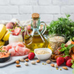 Vegans’ Longevity Myth Debunked by New Study A variety of fresh foods including fruits, vegetables, and oils arranged on a table