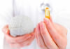 This Vitamin Deficiency Triggers Memory Decline A medical professional holding a brain model in one hand and a yellow supplement capsule in the other
