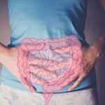 Aging Faster? Blame Your Gut, Not Your Genes Person holding their stomach with a graphic of intestines overlayed