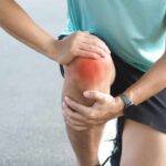 Sarcopenia’s Silent Spread: Are You at Risk? Athlete holding their knee in pain while exercising outdoors