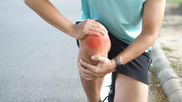 Athlete holding their knee in pain while exercising outdoors