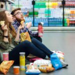 Aspartame in Sodas: The Unseen Threat to Kids A young couple sitting on the floor of a grocery store enjoying snacks