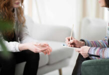 Two individuals engaged in a counseling session, one taking notes