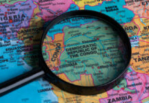 A magnifying glass focusing on the Democratic Republic of the Congo on a colorful map of Africa