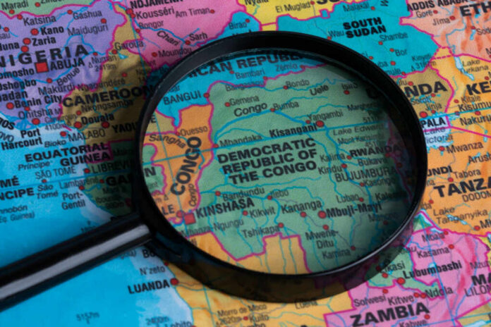 shutterstock_2223744101 A magnifying glass focusing on the Democratic Republic of the Congo on a colorful map of Africa