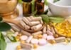 Vitamin B2’s Surprising Cancer Defense Various herbal supplements and vitamins arranged with leaves and a mortar