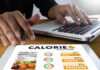 Yo-Yo Dieting: Metabolism Myths Exposed Person using a calorie counter app on a tablet while working on a laptop