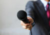 A person in a suit holding out a microphone