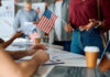 People participating in a voting event with American flags and paperwork