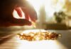 Silent Mineral Deficiency – Faster Wrinkles A hand reaching for a golden capsule among many on a table