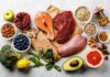 Assorted healthy foods with salmon, beef, chicken, fruits, vegetables, nuts, and grains
