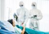 Healthcare workers in full PPE attending to a hospital patient