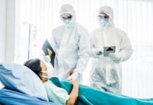 Healthcare workers in full PPE attending to a hospital patient