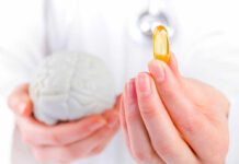 Best Brain Supplement of 2026 — 7.5 Years Younger Brain! A medical professional holding a brain model in one hand and a yellow supplement capsule in the other