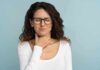 Woman with glasses touching her throat