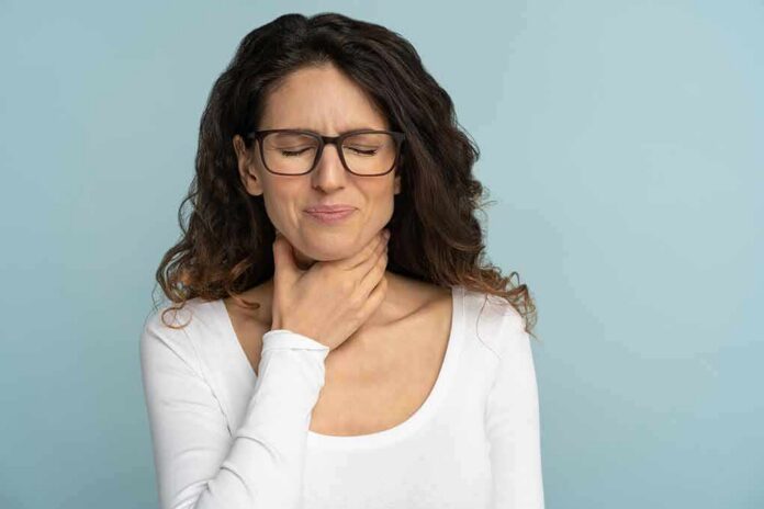 Woman with glasses touching her throat