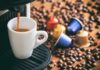 Espresso machine pouring coffee into a white cup with coffee pods and beans