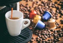 Espresso machine pouring coffee into a white cup with coffee pods and beans