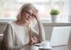 Older woman with glasses looking concerned at laptop