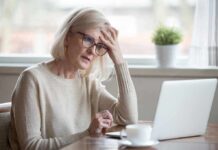 Older woman with glasses looking concerned at laptop