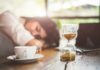 Terrifying Sleeping Beauty Syndrome Explained Hourglass on table with coffee cup and sleeping person in background