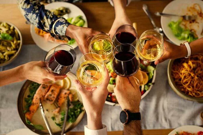 Hands clinking wine glasses over a dinner table