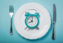 Alarm clock on a white plate with fork and knife
