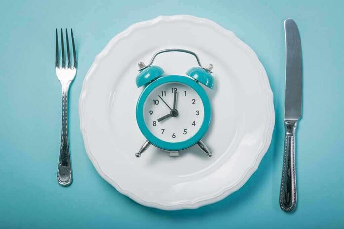 Alarm clock on a white plate with fork and knife