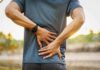 Person holding lower back in pain outdoors