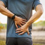 Person holding lower back in pain outdoors