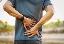Person holding lower back in pain outdoors