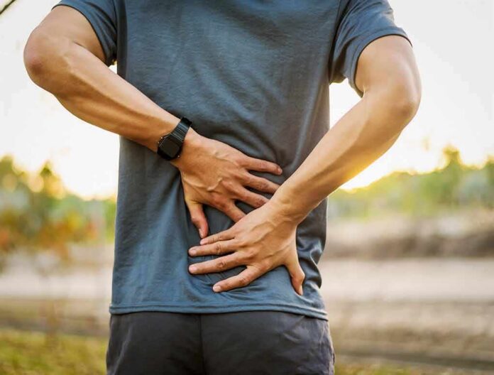 1783890432455-71vm8i-shutterstock-1020731773 Person holding lower back in pain outdoors
