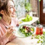 Woman eating a fresh salad at a bright cafe