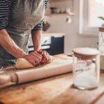 Person kneading dough on a wooden kitchen counter