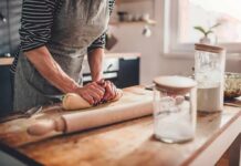 Person kneading dough on a wooden kitchen counter