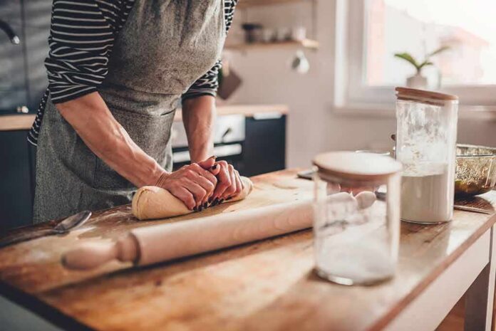 Person kneading dough on a wooden kitchen counter