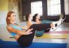 Women practicing boat pose on yoga mats in a studio