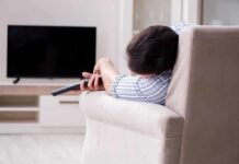 Too Much Sleep, Dementia Warning! Person lying on a sofa holding a TV remote
