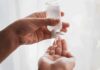 Hands dispensing sanitizer gel from a small bottle