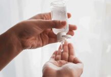 Hands dispensing sanitizer gel from a small bottle