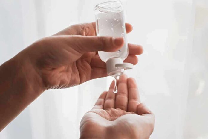 Hands dispensing sanitizer gel from a small bottle