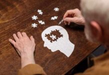 Hands assembling a head-shaped jigsaw puzzle on a wooden table