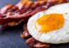 Fried egg with crispy bacon on dark surface