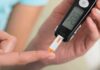 person using a blood glucose meter with a test strip